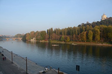 Torino 'daki Po nehri Murazzi tarafından fotoğraflandı. Nehirde yüzen kanocular Monte dei Capuccini 'nin üzerinde durduğu tepenin altında yelken açarlar..