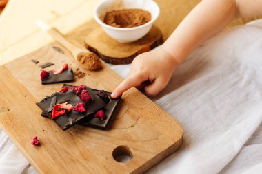 Kırık siyah çikolata parçası Childs 'ın ellerinde. Bebek diyeti, yemek, bebek ve şeker.