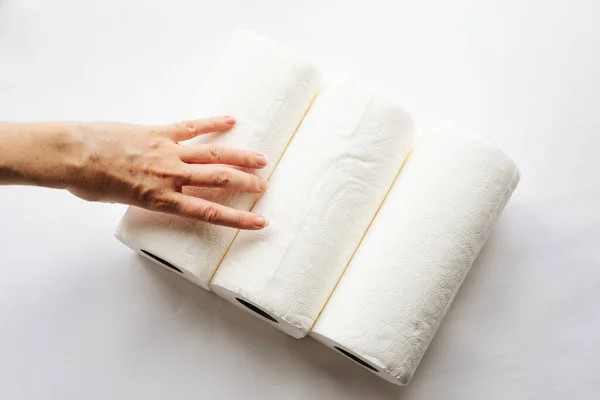 Női kezek, amik papírtörlő tekercseket, szalvétákat tartanak fehér alapon. Fehér a fehéren, cellulóz, papír, higiénia. A tudatos fogyasztás fogalma, fenntartható életmód. — Stock Fotó