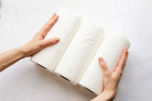 Női kezek, amik papírtörlő tekercseket, szalvétákat tartanak fehér alapon. Fehér a fehéren, cellulóz, papír, higiénia. A tudatos fogyasztás fogalma, fenntartható életmód. — Stock Fotó