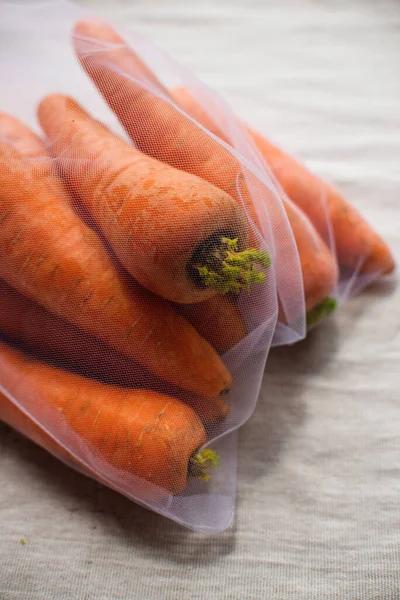 Nahaufnahme von Karotten in wiederverwendbarem Öko-Beutel. Pflanzenzüchtung, Kochen, gesunde Ernährung. Vegetarisches Essen. Bewusster Konsum. — Stockfoto