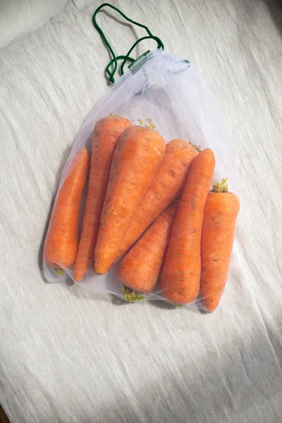 Nahaufnahme von Karotten in wiederverwendbarem Öko-Beutel. Pflanzenzüchtung, Kochen, gesunde Ernährung. Vegetarisches Essen. Bewusster Konsum. — Stockfoto
