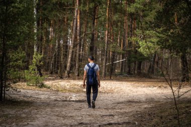 Genç adam ormanda yürüyor.