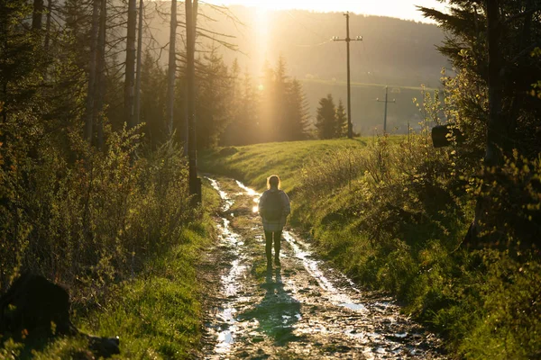 Bir kız sıcak güneş ışınlarıyla dolu bir yolda yürüyor.