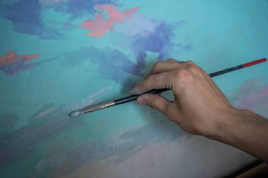 Tabloyu yağlı boyayla boyayan sanatçının eli.