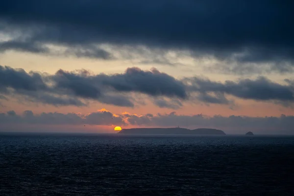 Fabelaktig solnedgang, solen går ned bak øya i det fjerne. – stockfoto