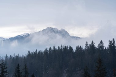 Bulutlar ve sisli karla kaplı dağların inanılmaz manzarası