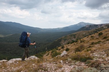 Kırım dağlarında sırt çantalı bir turist yüksek bir dağdaki mesafeye bakıyor.