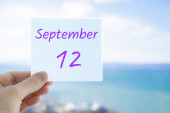 12. září. Ruční nálepka s textem 12. září na rozmazaném pozadí moře a oblohy. Kopírovat prostor pro text. Měsíc v koncepci kalendáře.