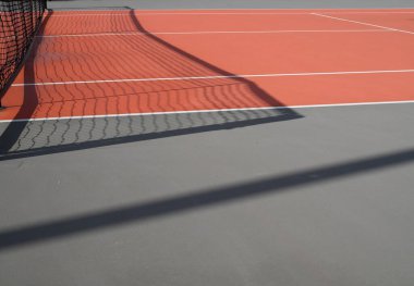 Siyah tenis ağı kırmızı tenis kortunu gölgeliyor. Spor ve aktivite kavramı