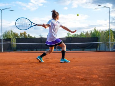 Tenis oyuncusu. Raketli güzel kız tenis kortunda topa vuruyor.