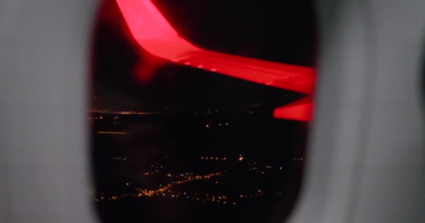 Vista da janela plana da cidade noturna e da asa do avião — Vídeo de Stock