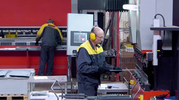 Arbetstagare operatör bockning metallplåt process med plåt bockning maskin för busstillverkning del, stål vikning med maskin Stockfoto