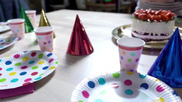 Праздничный стол украшен на день рождения цветными, одноразовыми бумажными тарелками, а также крышками и тортом — стоковое видео