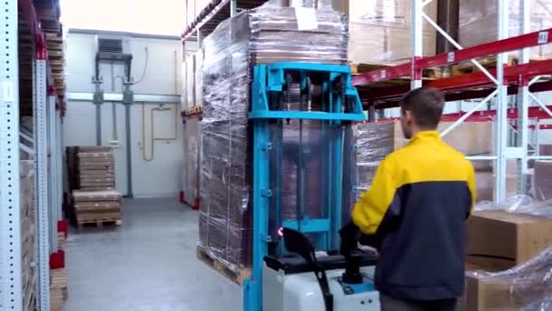 Conductor del trabajador de almacén en cajas de cartón de carga uniforme por cargador de apilador de carretilla elevadora — Vídeos de Stock