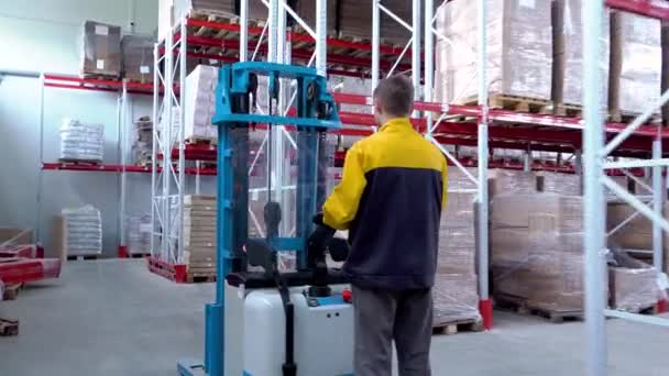 Warehouse worker driver in uniform loading cardboard boxes by forklift stacker loader — Stock Video