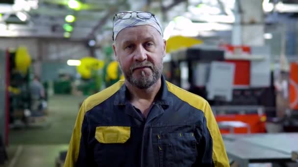 Retrato de empregado de fábrica com uma cara séria. Empregado na fábrica para a produção de produtos metálicos em uniforme olhar para a câmera — Vídeo de Stock