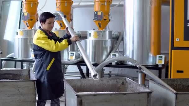 Trabalhador da planta de produção Trabalha com carregador Mangueira vácuo sugando grânulos de plástico virgem branca do tanque na oficina da fábrica — Vídeo de Stock