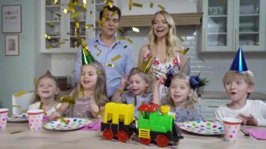 Beş çocuklu mutlu bir aile, baba ve anne kızlarının doğum gününü mutfakta kutluyor. Ailesi ona oyuncak tren hediye ediyor. Hepsi çocuk şapkalarının üzerinde şenlik kıyafetleri giymişti..