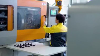 Operatör, kalpazanlık cihazından plastik ürünü çıkarıyor.