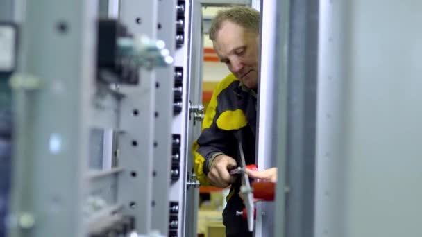 De man in het uniform aandraaien van de schroeven op metalen constructies in de fabriek voor de assemblage van transformatorbakken — Stockvideo