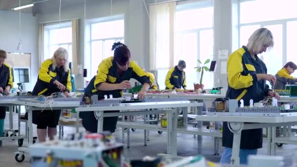 Arbeiterinnen in Uniform sammeln Niederspannungs- und Hochspannungsgeräte in der Fabrikhalle. Montage der Füllung für Transformatoren. 7 Frauen in Uniform arbeiten in der Fabrik — Stockvideo