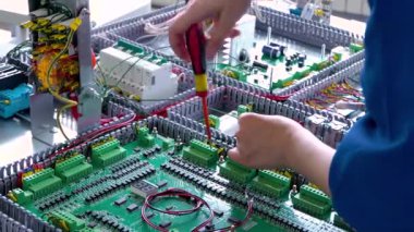 Montaj hattında kablolar ve kablolarla çalışan elektrikçiye yakın çekim, trafonun kurulumu