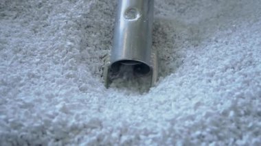 Elektrik süpürgesi hortumu fabrika atölyesindeki tanklardan beyaz bakir plastik granülleri emiyor.