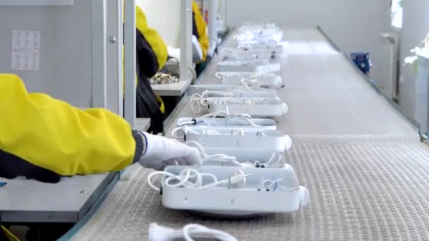 Vervaardiging van elektrische producten. Handen in witte handschoenen op de transportband afgewerkte producten. Vervaardiging van elektrische tegels en kachels. Sluiten. — Stockvideo