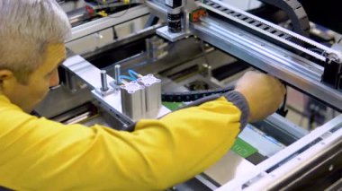 Mühendis, bakım ve temizlik için SMT, elektronik ekipmanlara yer, bulanık arkaplan, yüzey montaj teknolojisindeki nozülü makineden çıkarıyor.
