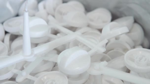 Een groot aantal kleine witte plastic onderdelen in de fabriek — Stockvideo