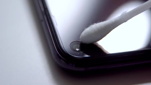 Mão com um cotonete para limpar a câmera do smartphone — Vídeo de Stock