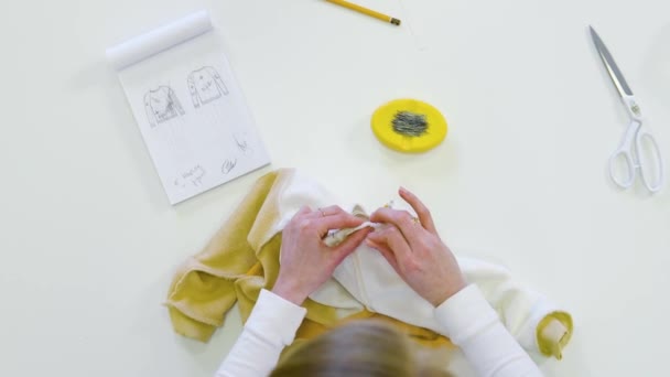 Modedesignerin, Schneiderin, die Stoff schneidet, während sie mit Zeichnungen arbeitet, Material am Arbeitstisch. Bekleidungsgeschäft. Blick von oben — Stockvideo