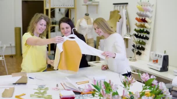 Aufnahme von drei Modedesignern, die in der Näherei an Details der neuen Kleiderkollektion arbeiten und entscheiden — Stockvideo