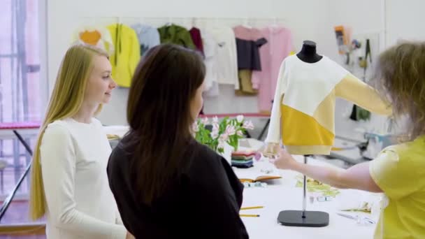 Tiro de tres diseñadores de moda trabajando y decidiendo los detalles de la nueva colección de ropa en el taller de costura — Vídeos de Stock