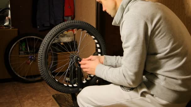 Fiets onderhoud. de jonge man haalt de spaken van de fietswiel. — Stockvideo
