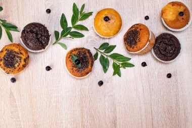 Çikolatalı kek ve fındıklı kek, arka planda ev yapımı fırın. Ahşap bir masada yaban mersinli kek. Tahtada taze böğürtlen ve tatlı börek var..