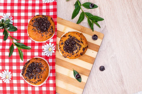 Çikolatalı kek ve fındıklı kek, arka planda ev yapımı fırın. Ahşap bir masada yaban mersinli kek. Tahtada taze böğürtlen ve tatlı börek var..