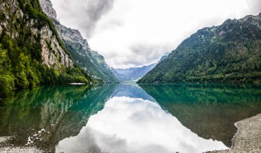 Klontalersee Gölü 'nde açık mavi yaz günü. Glarnisch, dağlık alan suya yansıyor. Güneş ışınları