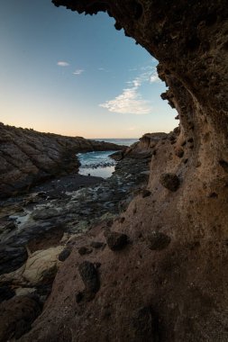 Kayalık volkanik taşlara, Tenerife 'ye, Kanarya Adalarına, İspanya' ya vuran dalgaların üzerine gün batımı ışığı