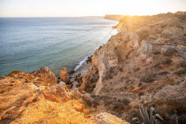 Lagos, Algarve Portekiz 'deki Praia do Camilo' ya güneş doğarken göz kamaştırıcı bir manzara. Kayalar, kayalıklar ve okyanustaki oluşumlar. Doğal hazine. Portekiz