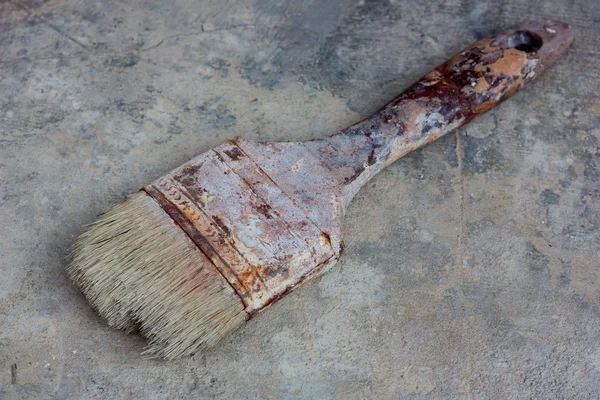 Old paint brush on cement floor.