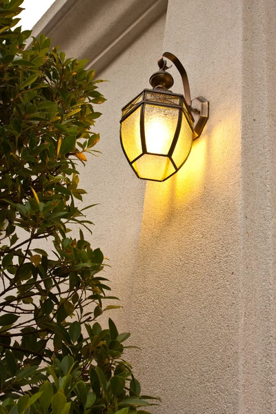 Antique wall lamp glowing orange in the evening. — Stock Photo, Image