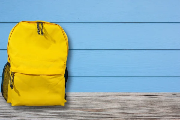 Torba ya da sırt çantası mavi duvarlı ahşap bir masa yerleştirilir.