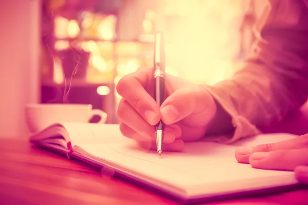 Yazmak üstünde belgili tanımlık defter bir kalem tutan adam el.