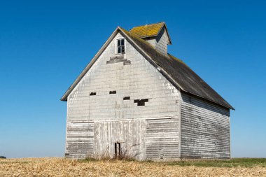 Arka planda mavi gökyüzü olan açık alanda eski bir ahır. LaSalle County, Illinois, ABD