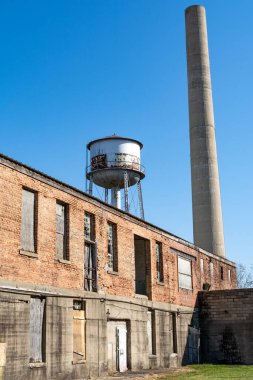 Terk edilmiş bir sanayi bölgesinde terk edilmiş bir duman ve su kulesi. Amboy, Illinois.