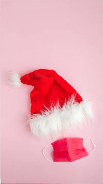 Covid-19 salgını sırasında Noel 'i ve yeni yılı kutlamak için yaratıcı asgari konsept. Pembe arka planda yüz maskesi olan Noel Baba şapkası. Sosyal medya hikayeleri biçimi 16: 9 düz