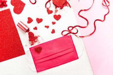 COVID-19 salgını sırasında Sevgililer Günü için yaratıcı fikirler. Kırmızı kalp koruyucu bir maske takıyor. Düz yatıyordu,