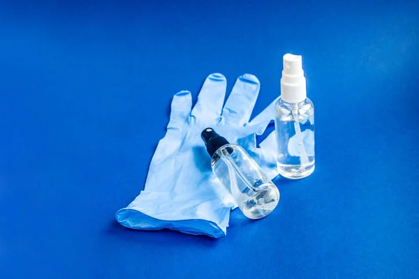 Blue gloves and two pump spray hand picked antiseptic spray on blue background. COVID-19 protection concept — Stock Photo, Image
